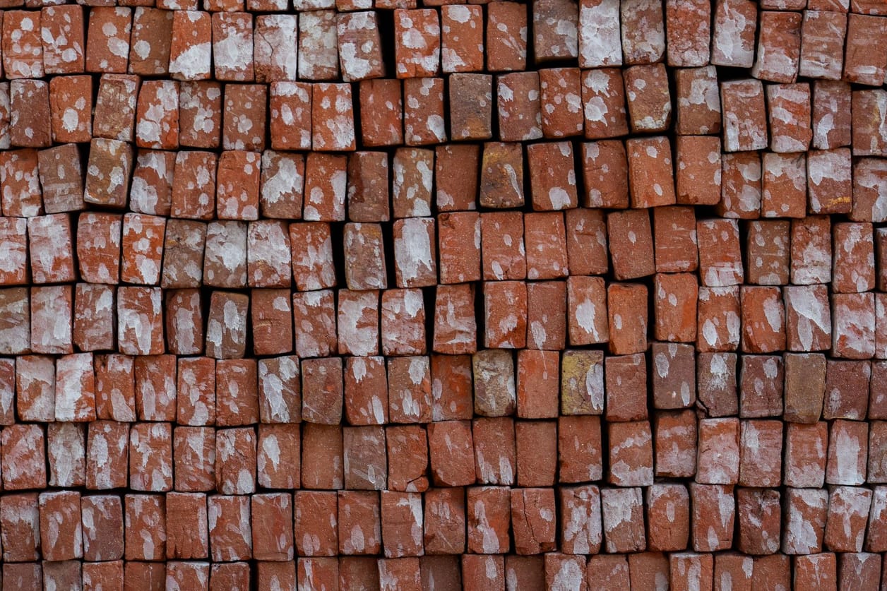 Pilha de tijolos cerâmicos vermelhos empilhados em paletes